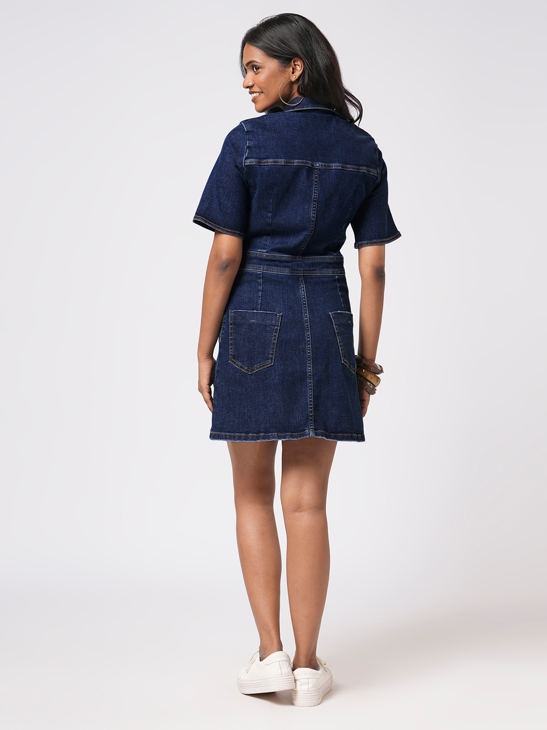 Woman wearing a Rerasa denim dress on a white background
