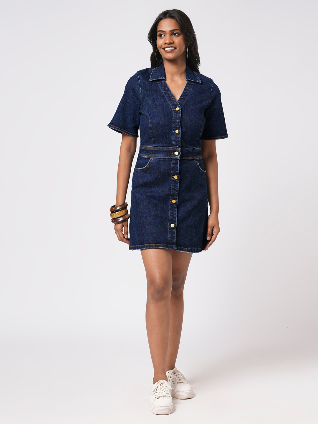 Woman wearing a Rerasa denim dress on a white background