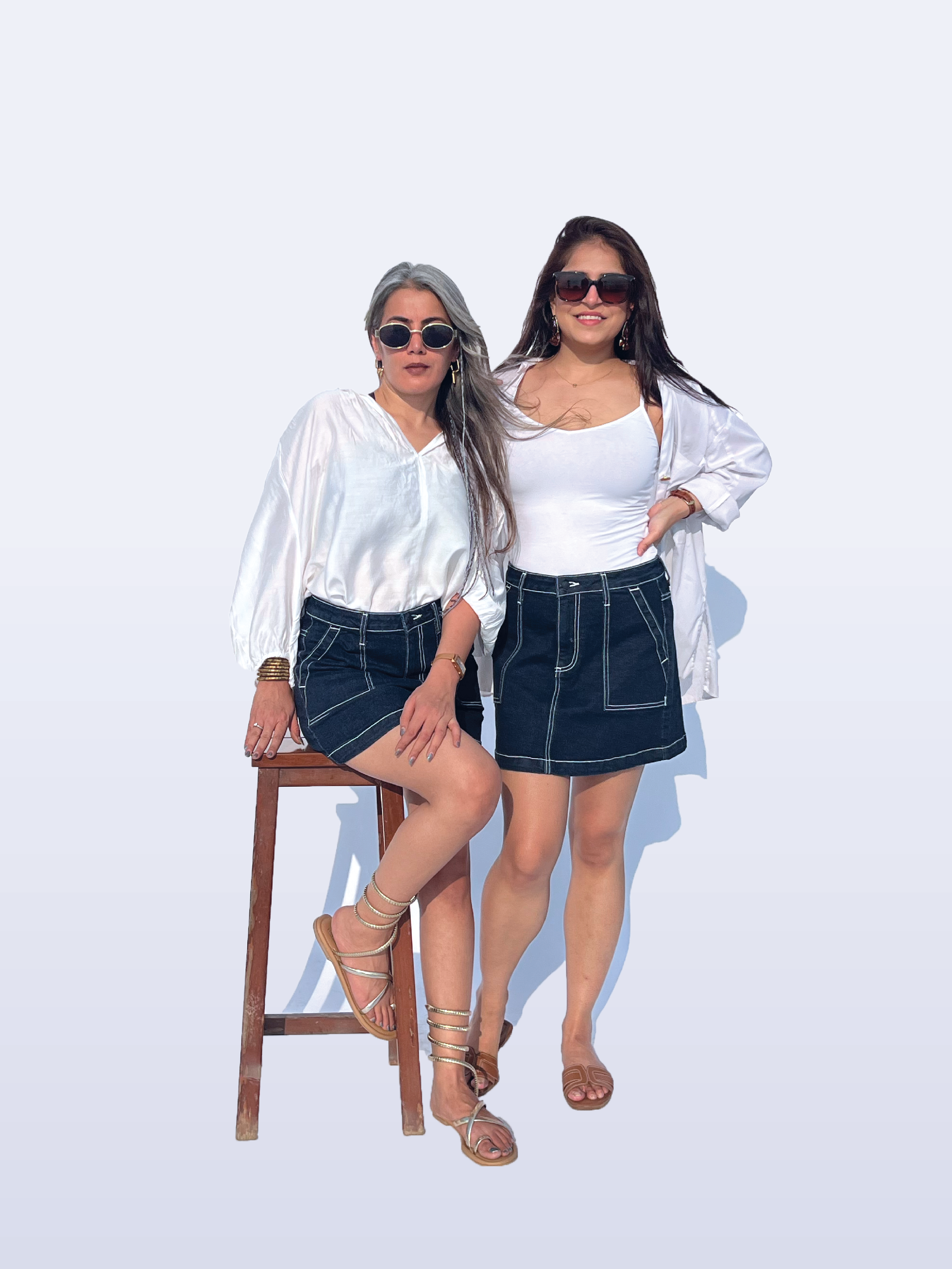 Two women wearing white tops and Rerasa denim skirts posing against a white background.