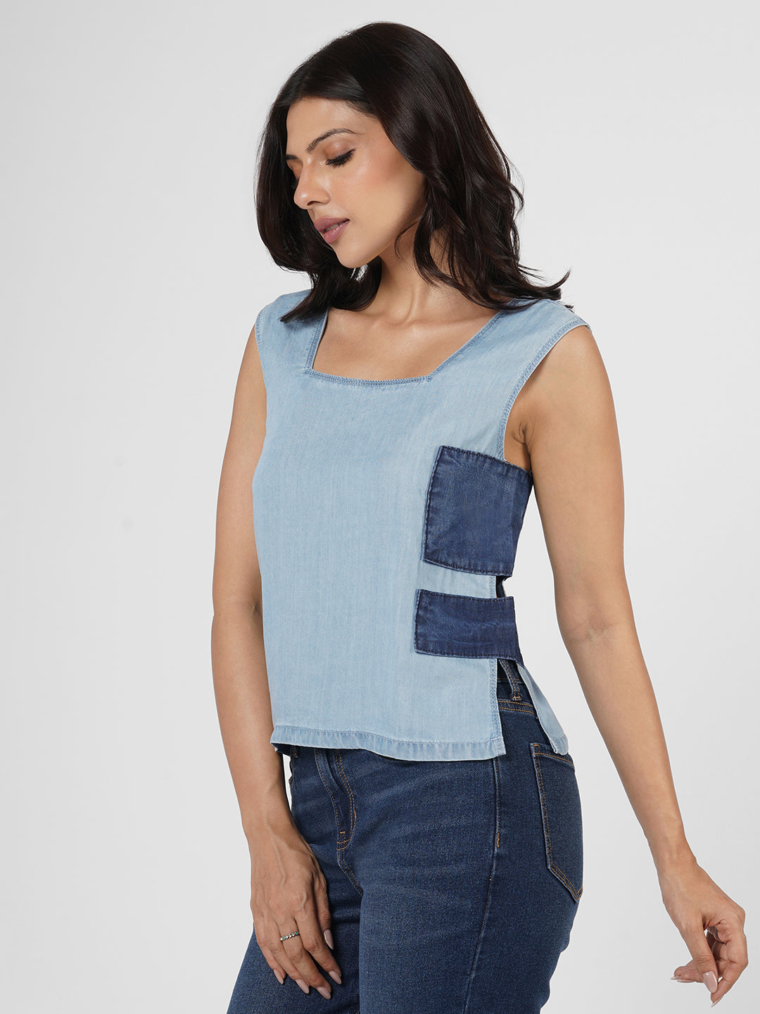 Woman wearing a light blue sleeveless top with denim accents on a white background Rerasa