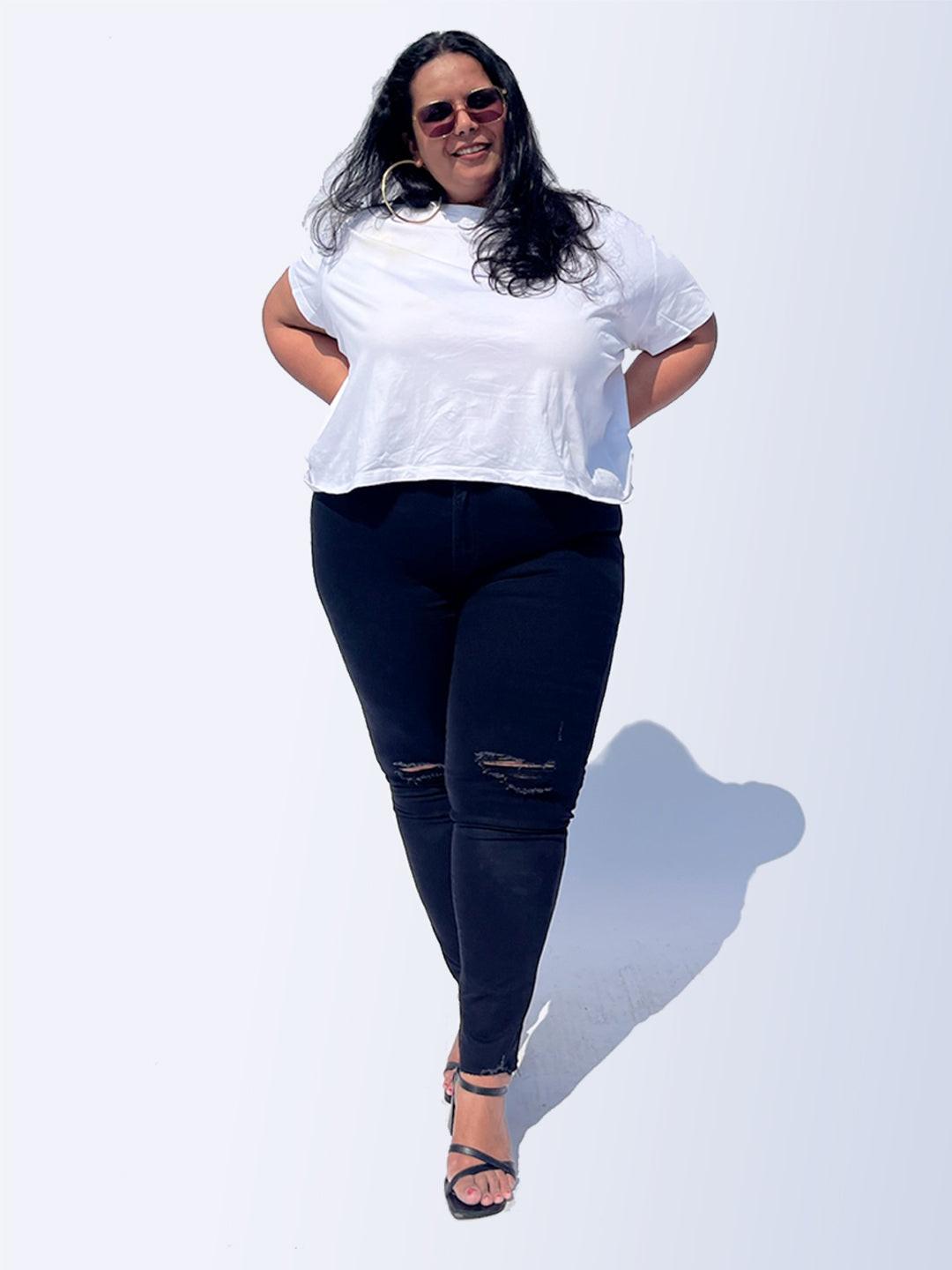 Woman wearing a white t-shirt and Rerasa black jeans against a white background